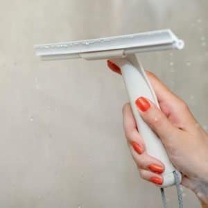 Cleaning the glass in the shower of a transportable cabin with a squeegee