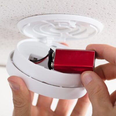 Person's Hand Inserting Battery In Smoke Detector Changing the smoke alarm battery in a transportable cabin
